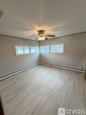 Levittown house for rent - A room with a ceiling fan and three windows.