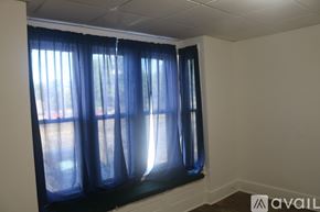 Hutchinson apartment for rent - A room with a window covered by blue curtains.