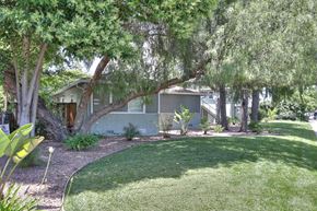 Mountain View apartment for rent - A building is surrounded by a green lawn and trees.