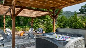 Fairview house for rent - A hot tub is surrounded by chairs and a fire pit under a wooden pergola.
