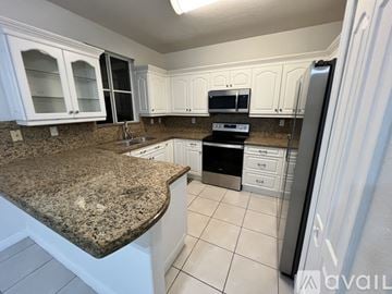 Hialeah townhouse for rent - A kitchen with a stainless steel refrigerator and white cabinets.
