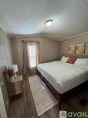 Selma apartment for rent - A bedroom with a bed, nightstand, and window with curtains.