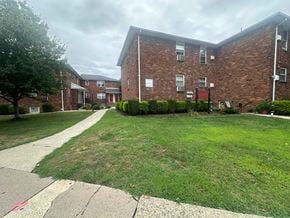 Rutherford apartment for rent - A grassy area in front of a brick building with a sidewalk.