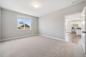 River Falls house for rent - A spacious room with a carpeted floor and a window showing a house outside.