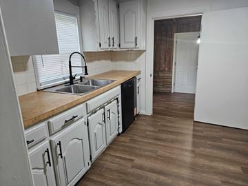 Choctaw house for rent - A kitchen with white cabinets and a brown countertop.
