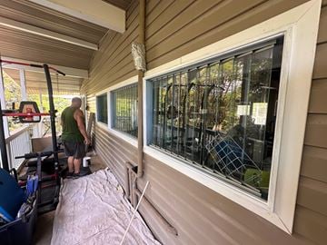 Kailua-Kona apartment for rent - A man in a green shirt is working on a window on a house.