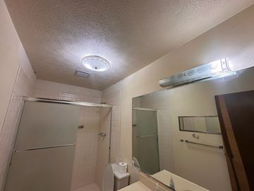 Kailua-Kona apartment for rent - A bathroom with a toilet, sink, mirror, and shower.
