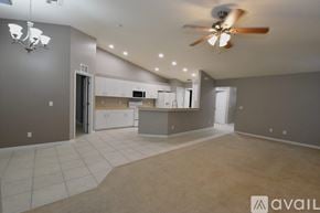 Lehigh Acres apartment for rent - A spacious living room with a ceiling fan and a kitchen area in the background.