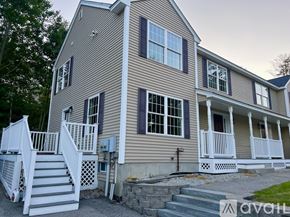 Milford townhouse for rent - A two-story house with a white porch and a stone wall.