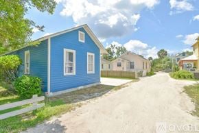 St. Augustine house for rent - A blue house with a white fence and a dirt road in front.