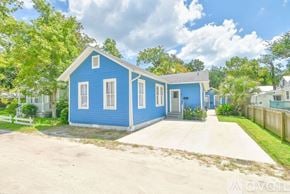 St. Augustine house for rent - A blue house with a white fence and trees in the background.