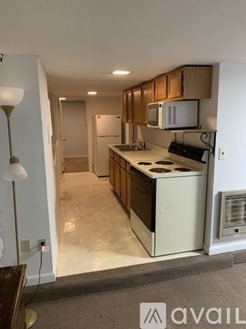 Berry Hill house for rent - A kitchen with wooden cabinets and a white fridge.