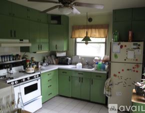 Syracuse house for rent - A kitchen with green cabinets and a white refrigerator.