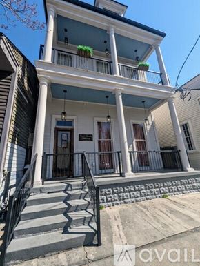 New Orleans apartment for rent - A two-story house with a front porch and stairs leading up to the entrance.