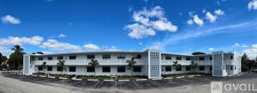 North Palm Beach apartment for rent - A large white building with multiple balconies and palm trees in front.
