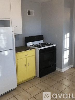 Kansas City house for rent - A kitchen with a white fridge, yellow cabinet, and black stove.