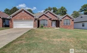 Little Rock house for rent - A brick house with a white garage door and a brown roof.