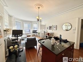 Boston apartment for rent - A kitchen with a black countertop and a dining area with a table and chairs.
