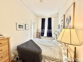 Boston apartment for rent - A bedroom with a bed, dresser, and lamp.