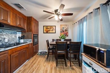 Sacramento house for rent - A kitchen with wooden cabinets and a dining table with chairs.