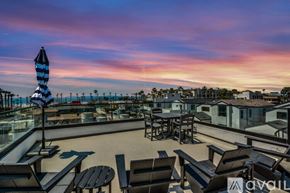 Huntington Beach condo for rent - A patio with a striped umbrella and chairs overlooking the ocean.