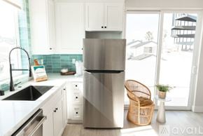 Huntington Beach condo for rent - A modern kitchen with a stainless steel refrigerator and white cabinets.