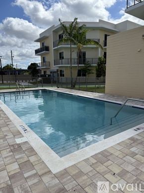 Miami apartment for rent - A swimming pool in front of a building with a balcony.