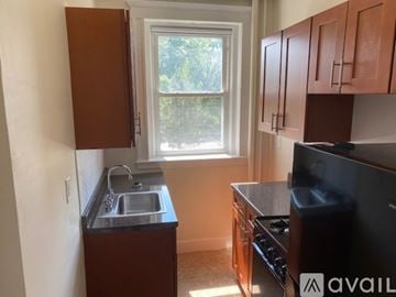 Boston apartment for rent - A kitchen with brown cabinets and a black stove top oven.