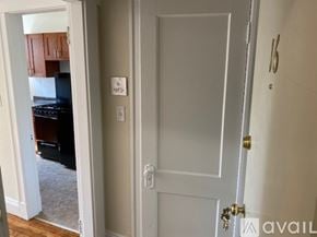 Boston apartment for rent - A white door with a gold handle is in a room with a white wall and a switch.