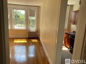 Boston apartment for rent - A room with wooden floors and a window overlooking a tree.