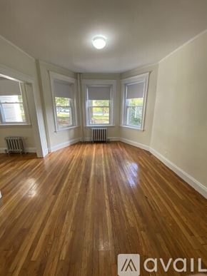 Boston apartment for rent - A room with wooden floors and three windows.