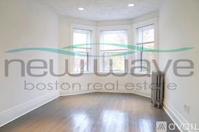 Boston apartment for rent - A room with a wooden floor and a window with a view of trees outside.