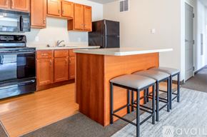 Whitewater apartment for rent - A kitchen with wooden cabinets and a black refrigerator.