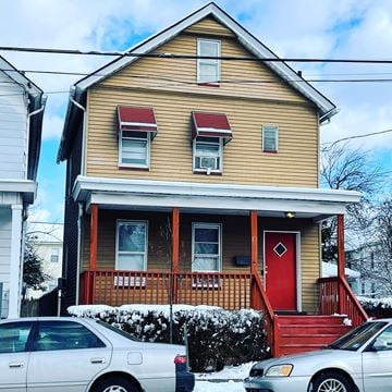 New Brunswick apartment for rent - A house with a red door and a red awning is in front of a white car.