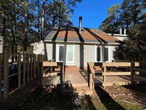 Wilson apartment for rent - A house with a grey exterior and a red roof is surrounded by trees.