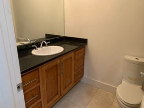 Washington apartment for rent - A bathroom with a white toilet and a sink with wooden cabinets.