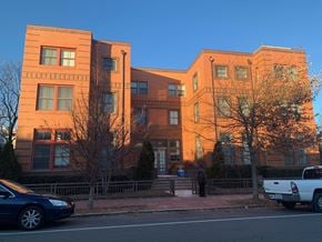 Washington apartment for rent - A blue car is parked on the side of the street in front of a brick building.