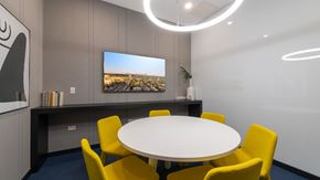 Oak Park apartment for rent - Private resident meeting room at Eleven33 Apartments in Oak Park featuring modern round table, yellow chairs, and mounted TV display.