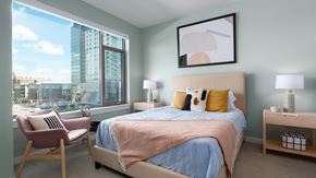 Oak Park apartment for rent - Bright bedroom at Eleven33 Apartments in Oak Park featuring large window, soft blue bedding, and modern furnishings.