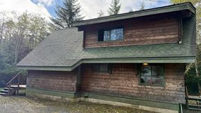Sitka house for rent - A wooden house with a green roof and a window.