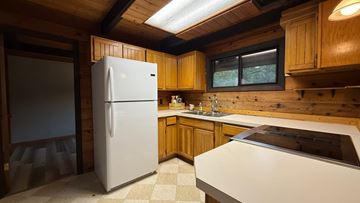 Sitka house for rent - A white refrigerator stands in a kitchen with wooden cabinets and a window.
