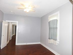 New Orleans apartment for rent - A room with a ceiling fan and a window with a curtain.