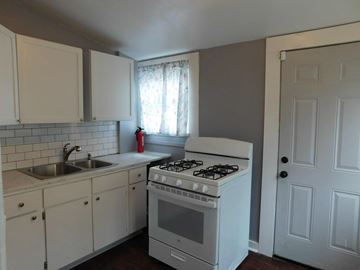 New Orleans apartment for rent - A white kitchen with a stove, sink, and cabinets.