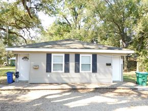 Hammond apartment for rent - A small house with a grey roof and a white door is surrounded by trees.