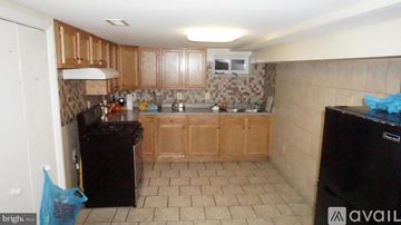 Baltimore townhouse for rent - A kitchen with brown cabinets and black appliances.