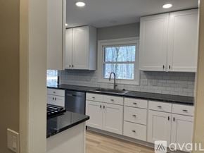 Rockford house for rent - A kitchen with white cabinets and a black countertop.