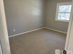 Rockford house for rent - A room with a carpeted floor and a window showing trees outside.