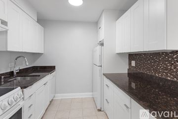 Chicago apartment for rent - A kitchen with white cabinets and a black countertop.