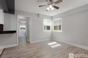 Chicago apartment for rent - A spacious room with a ceiling fan and light, hardwood flooring, and a window with blinds.