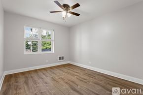 Chicago apartment for rent - A room with a ceiling fan and a window showing a view of trees.